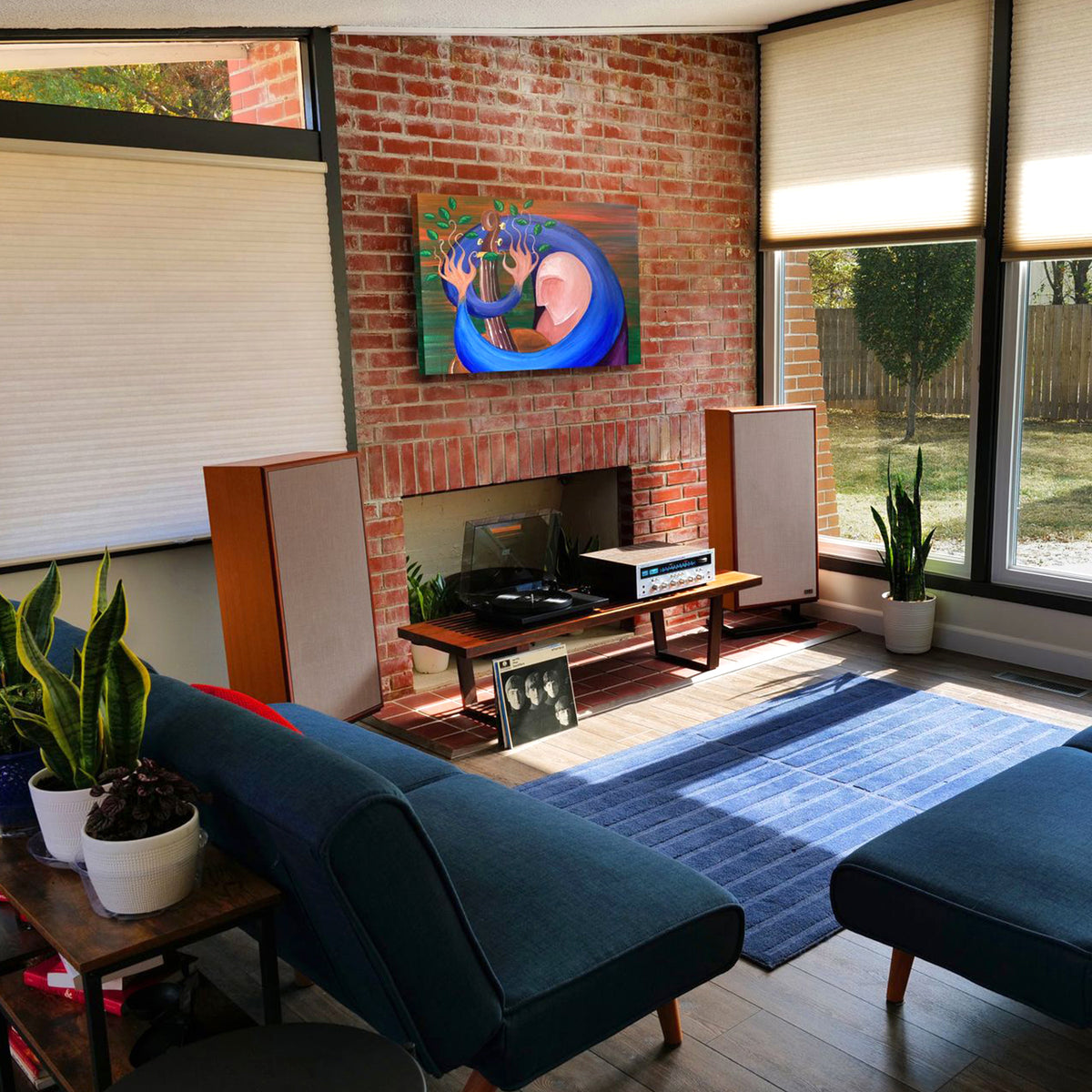 Modern living room with a brick wall, blue sofa, and large windows.