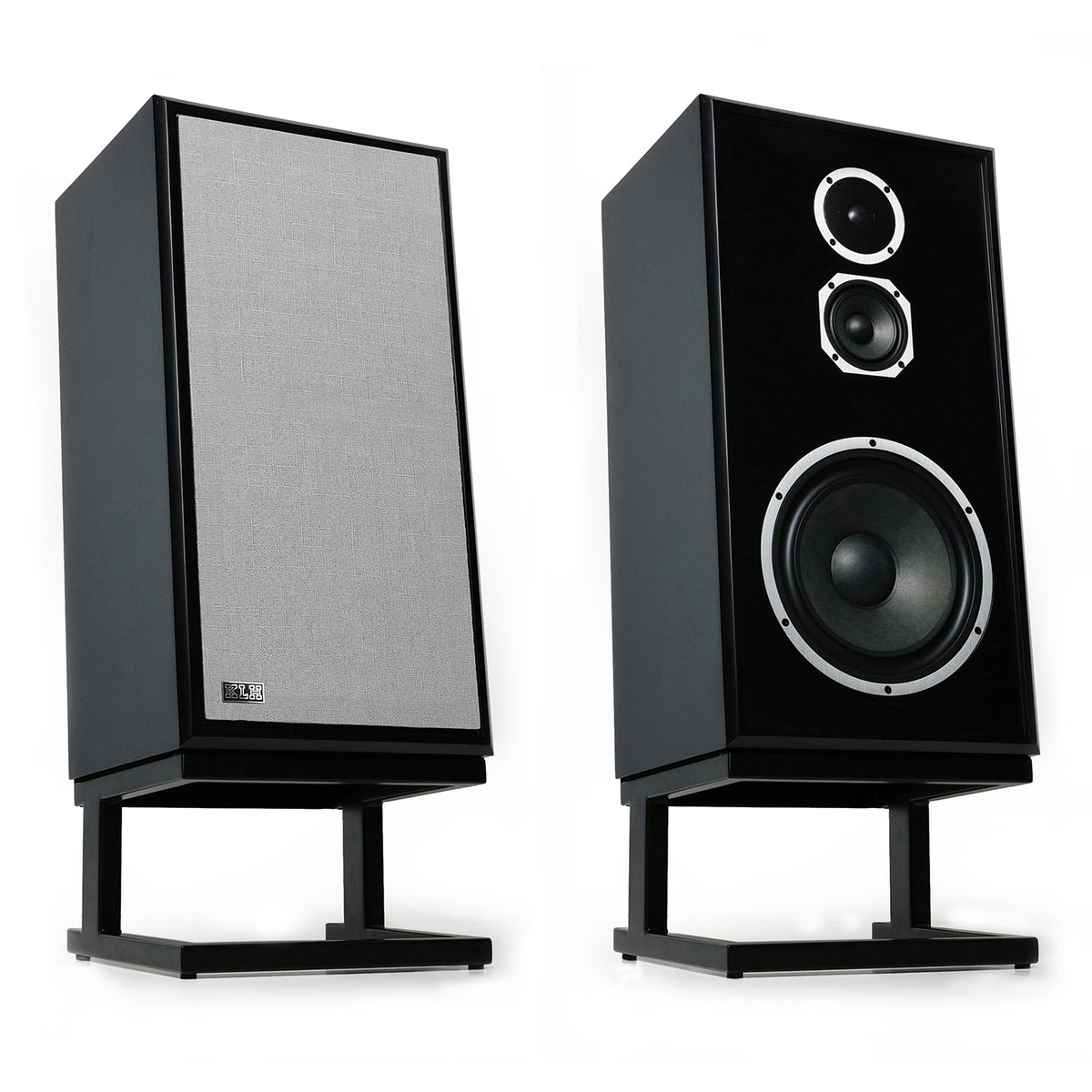 Two black bookshelf speakers on stands, one showing the front grille and the other showing the front face with two drivers, on a white background.