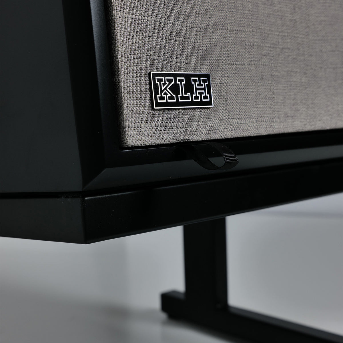 Close-up of a black speaker cabinet with a textured gray fabric grille and a black KLH logo badge on the front.