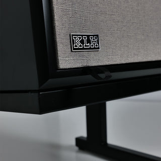 Close-up of a black speaker cabinet with a textured gray fabric grille and a black KLH logo badge on the front.